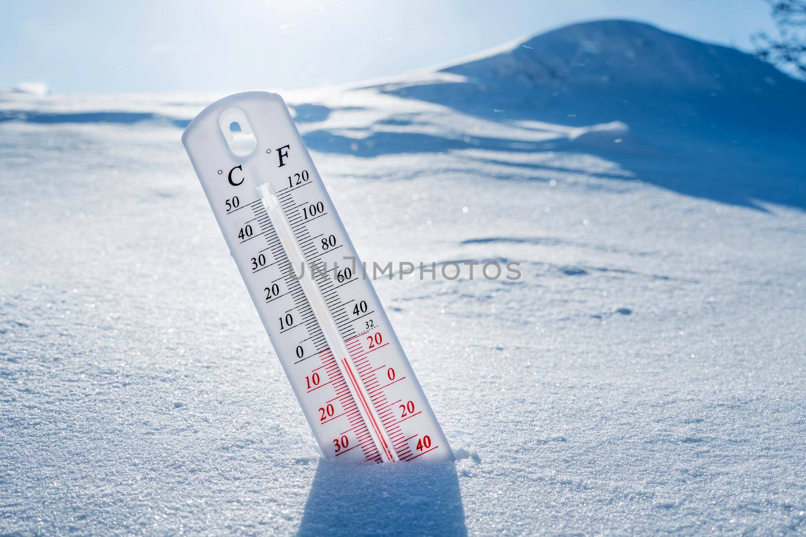 The thermometer lies on the snow in winter showing a negative temperature.Meteorological conditions in a harsh climate in winter with low air and ambient temperatures.Freeze in wintertime.Sunny winter by YevgeniySam