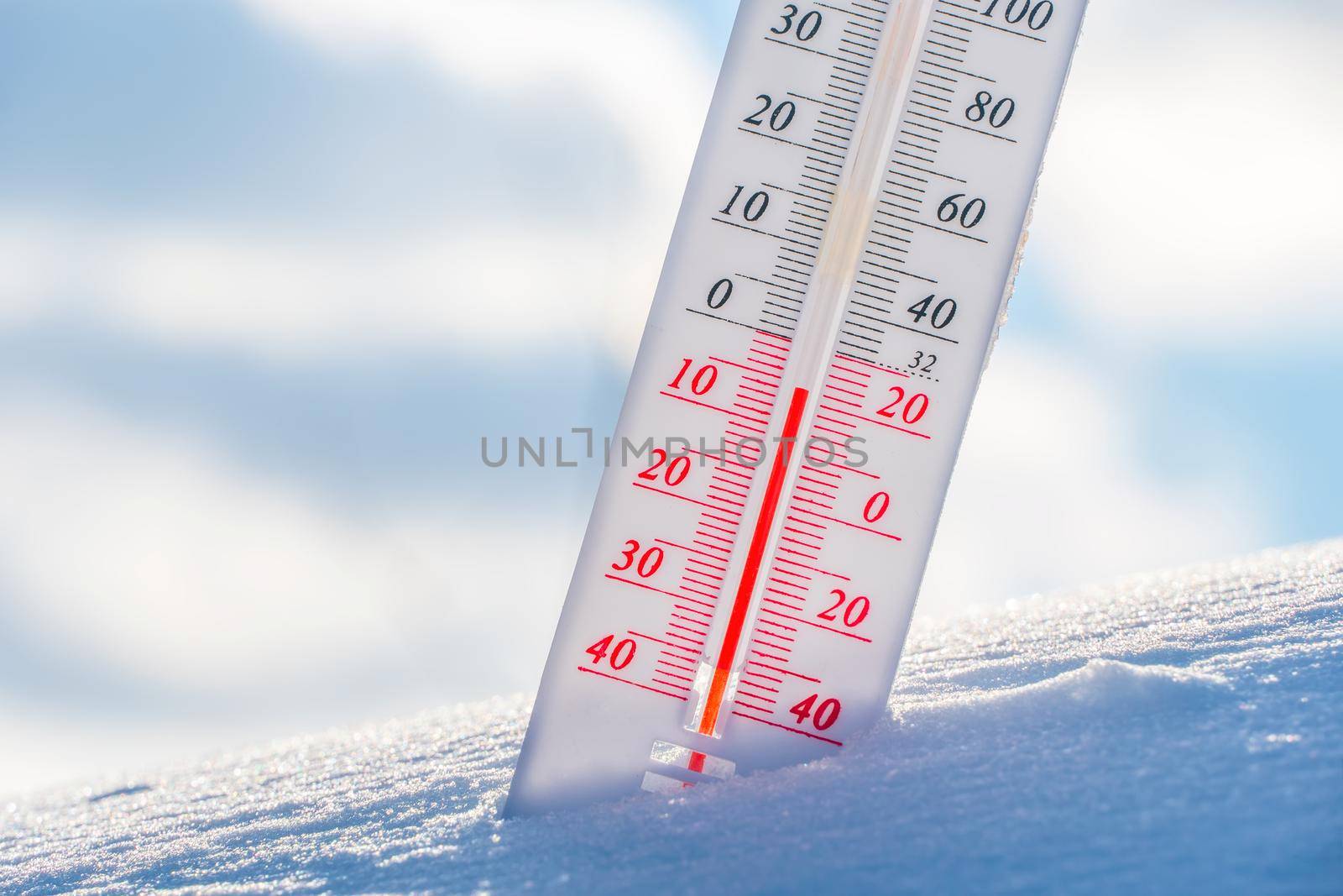 The thermometer lies on the snow in winter showing a negative temperature.Meteorological conditions in a harsh climate in winter with low air and ambient temperatures.Freeze in wintertime.Sunny winter