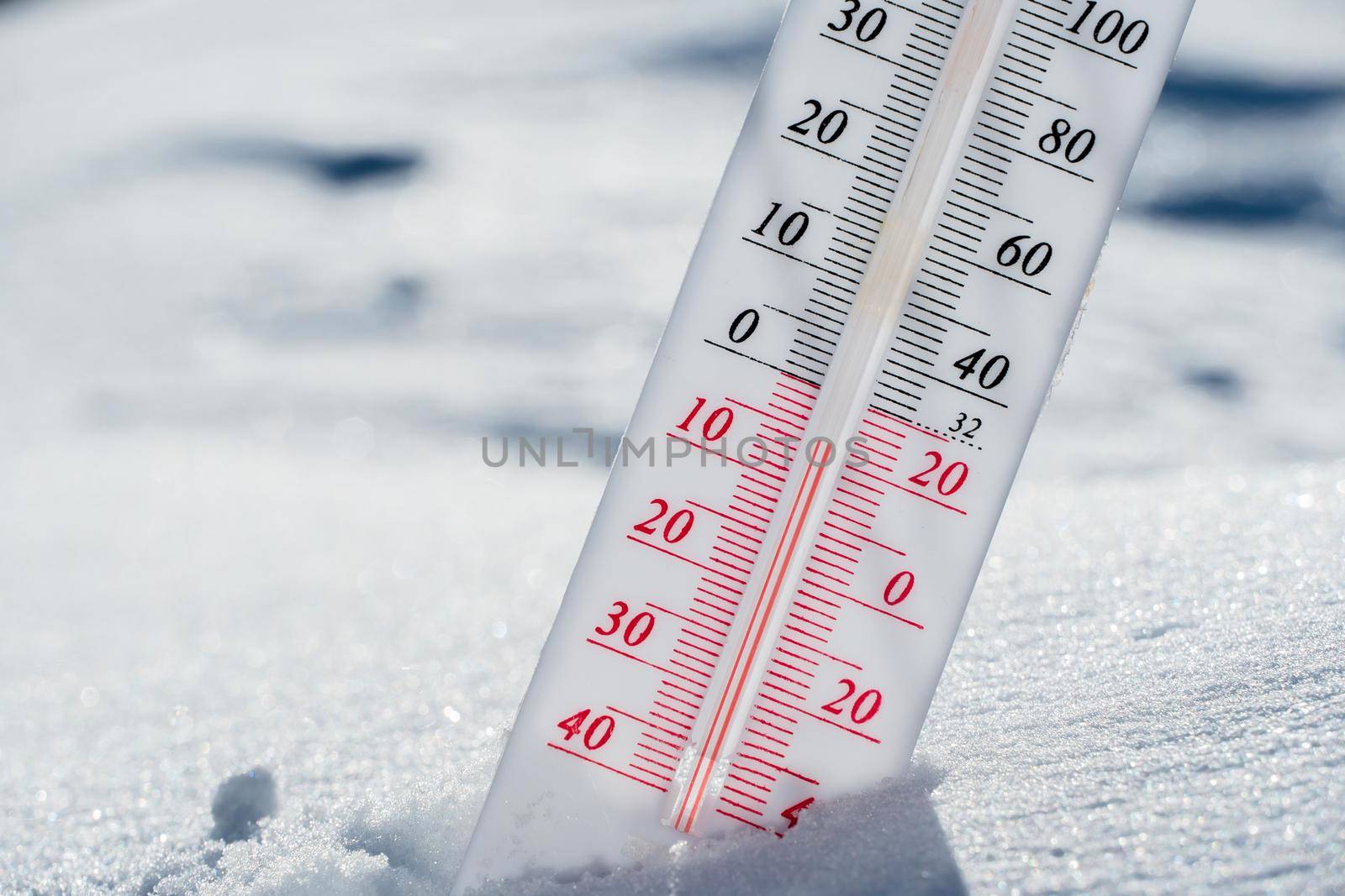 The thermometer lies on the snow in winter showing a negative temperature.Meteorological conditions in a harsh climate in winter with low air and ambient temperatures.Freeze in wintertime.Sunny winter by YevgeniySam