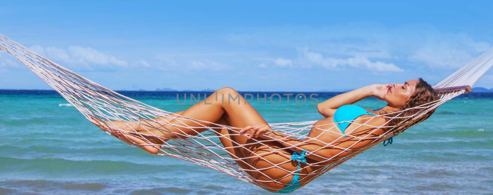 Young beautiful woman resting in hummock on tropical beach