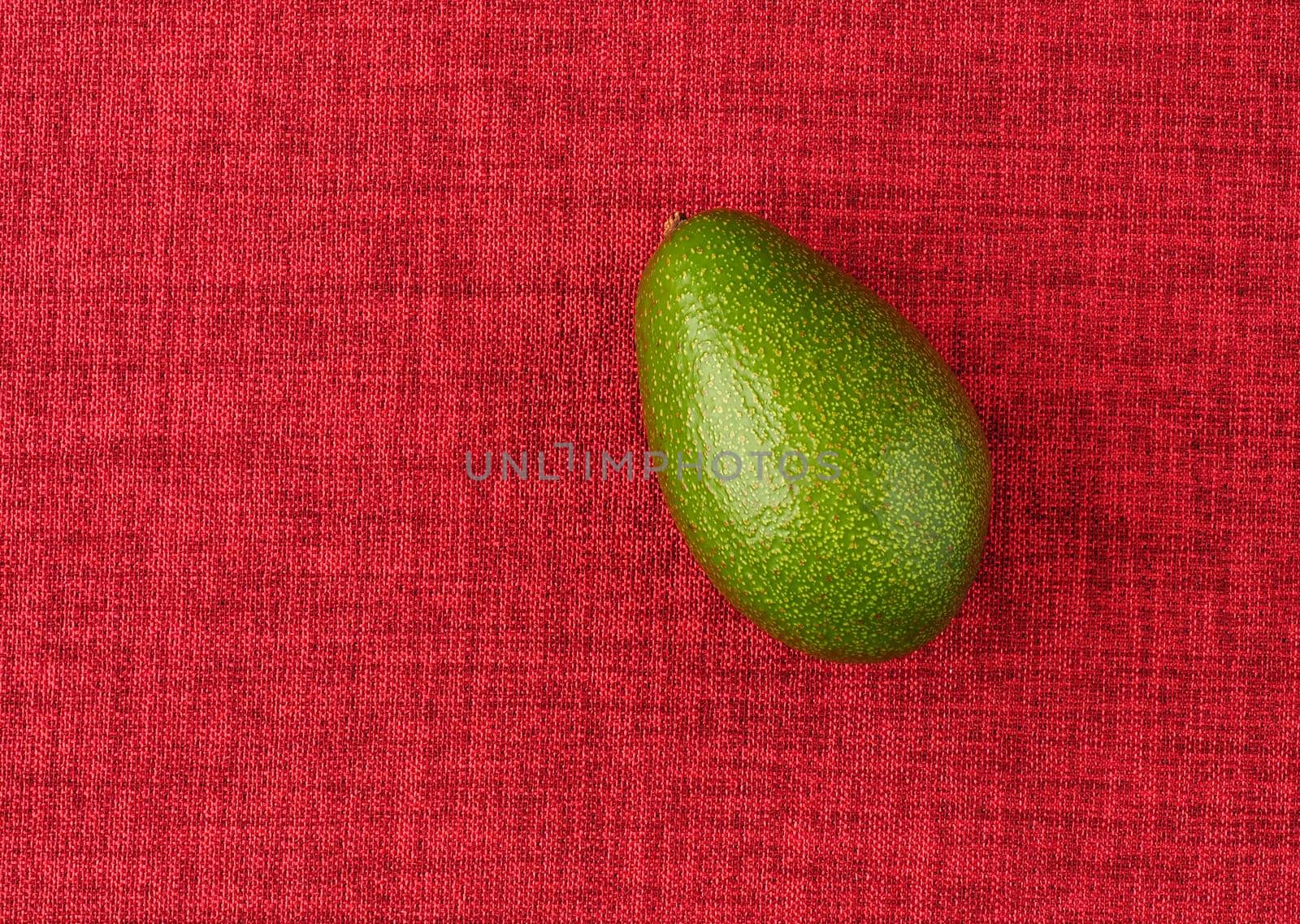 Avocado. The ripe fruit is green, on a red background, isolated, close-up. by Olga26