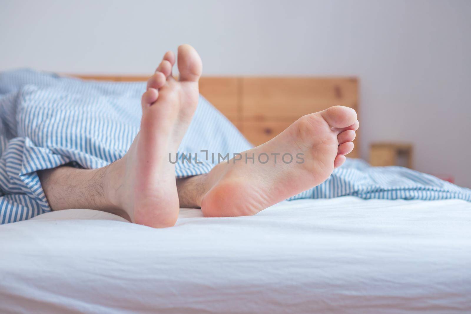 Close up uncovered female adult feet sleeping in bed, morning