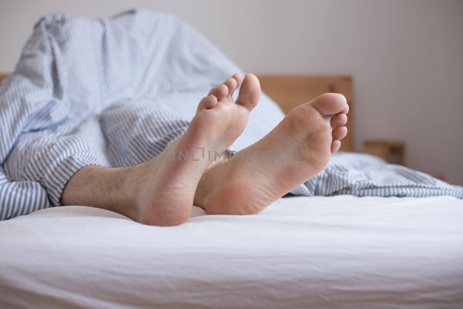 Close up uncovered female adult feet sleeping in bed, morning