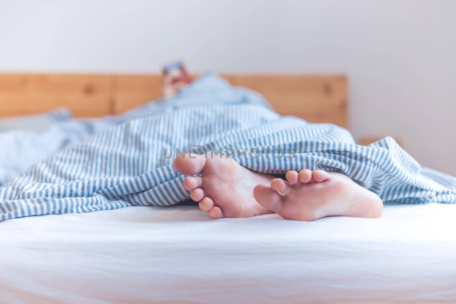 Close up a couples uncovered feet sleeping in bed, morning