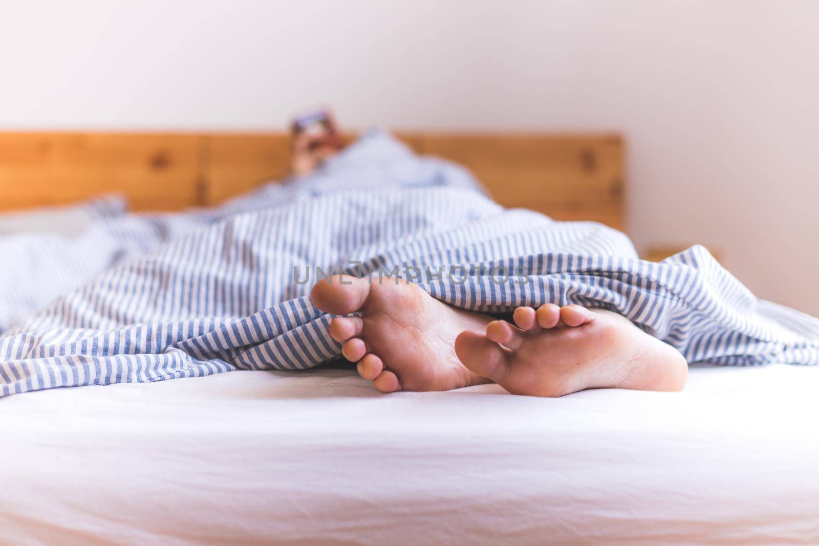 Close up a couples uncovered feet sleeping in bed, morning