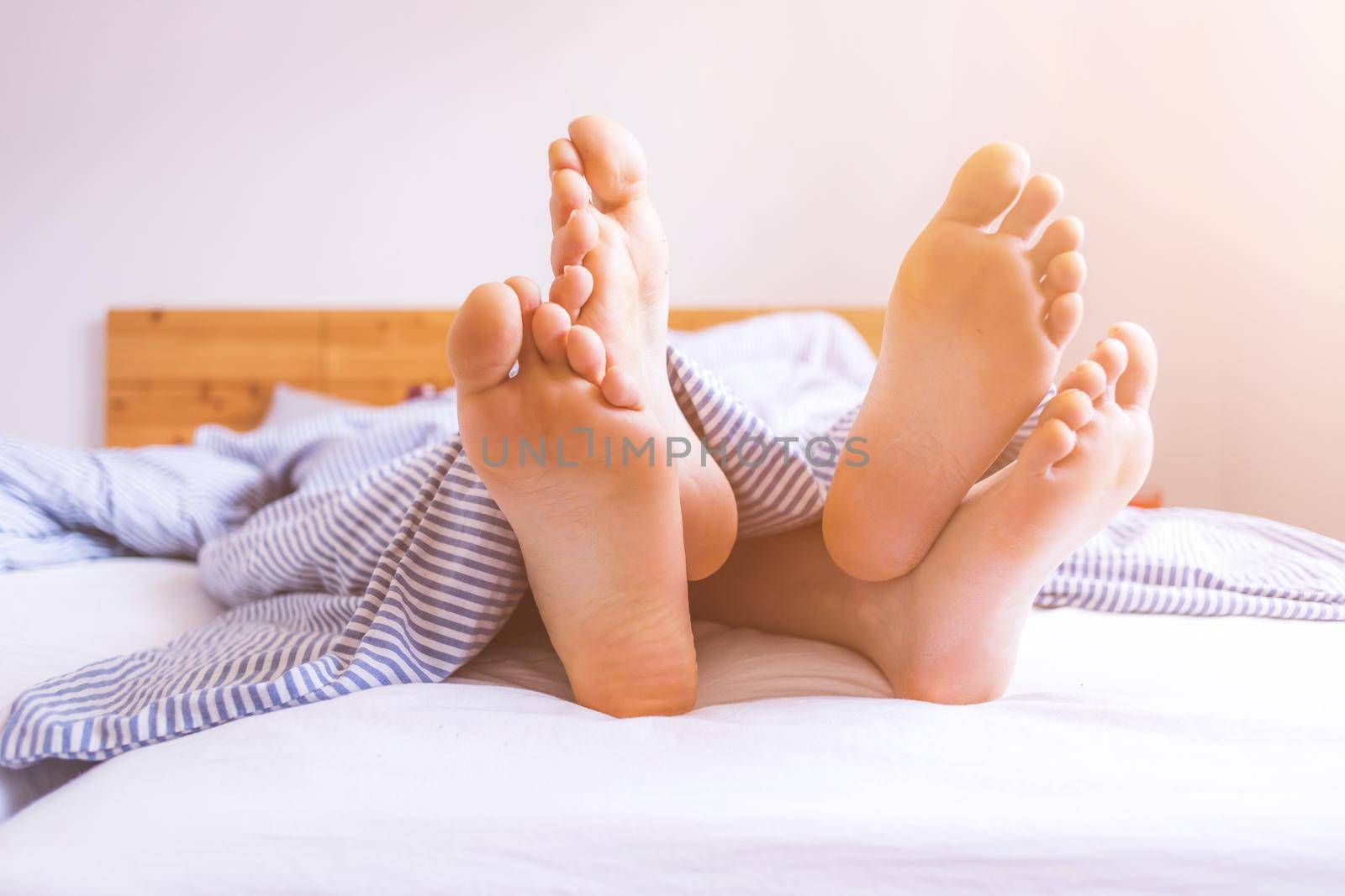Close up a couples uncovered feet sleeping in bed, morning