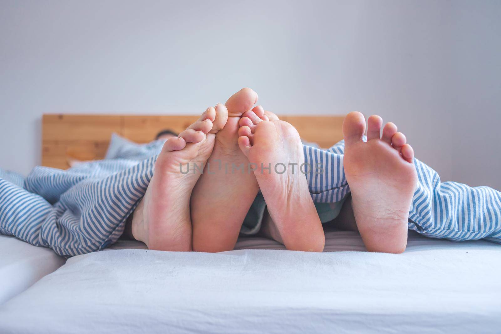 Close up a couples uncovered feet sleeping in bed, morning