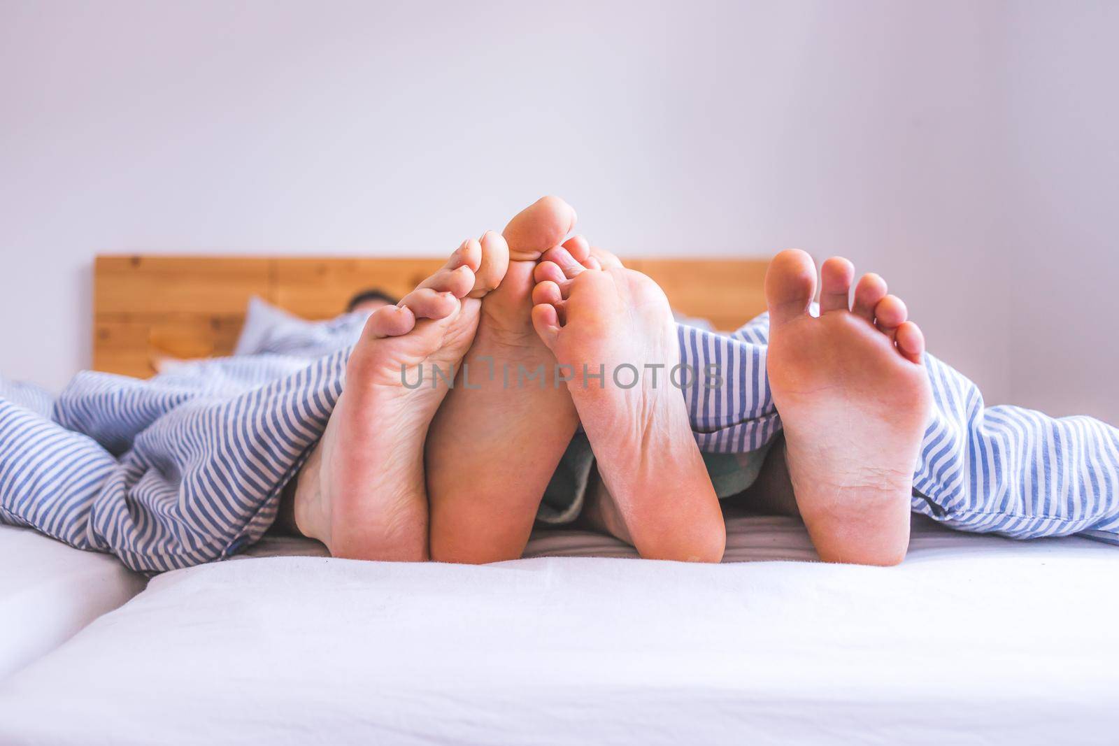Close up a couples uncovered feet sleeping in bed, morning