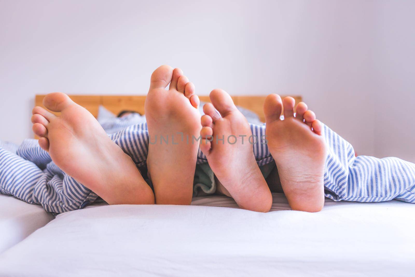 Close up a couples uncovered feet sleeping in bed, morning
