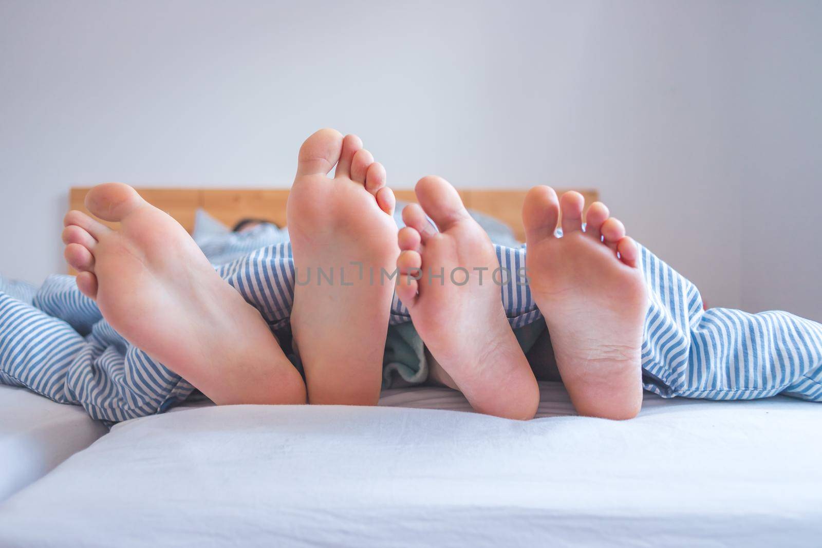 Close up a couples uncovered feet sleeping in bed, morning