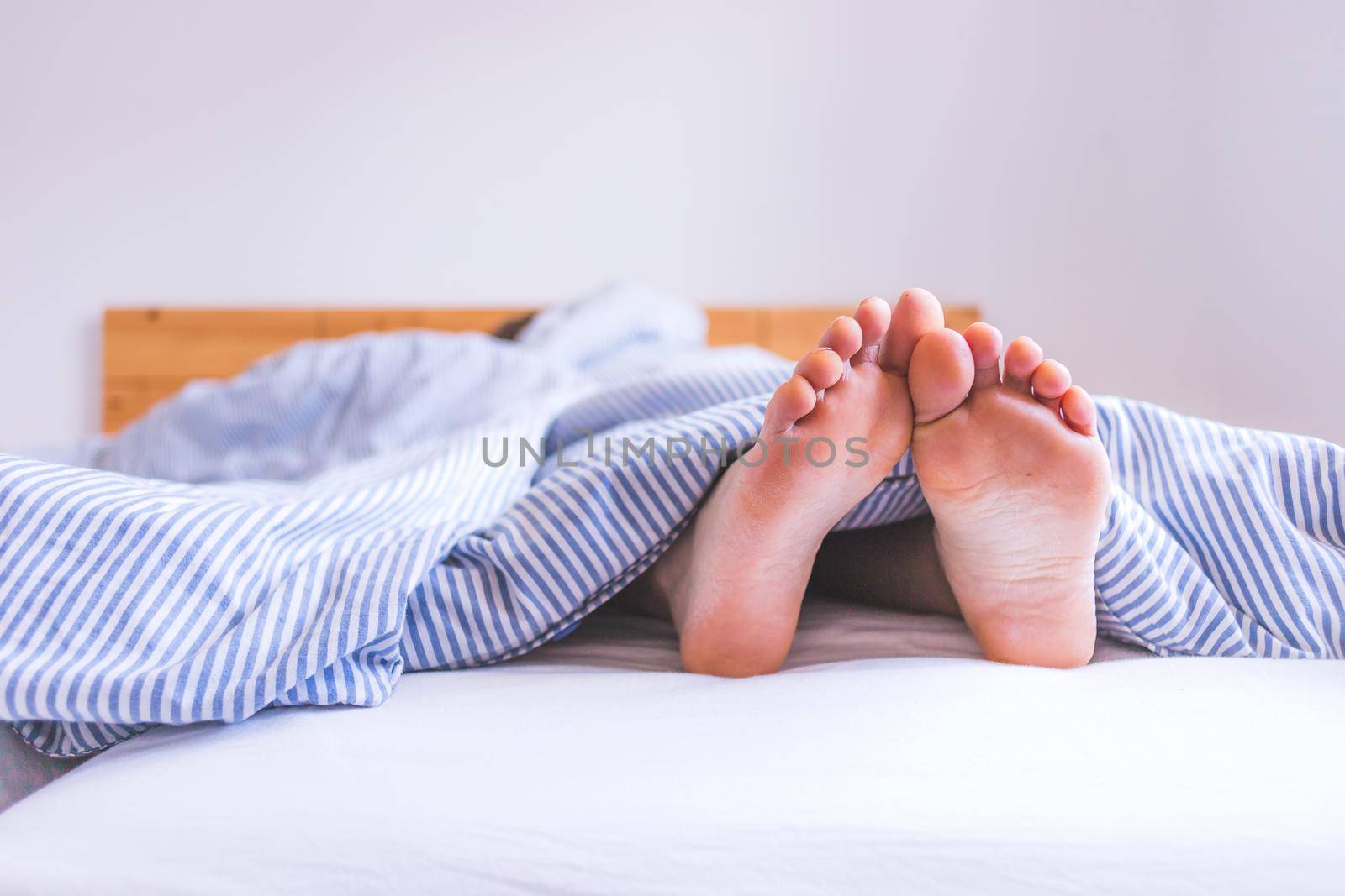Close up uncovered female adult feet sleeping in bed, morning