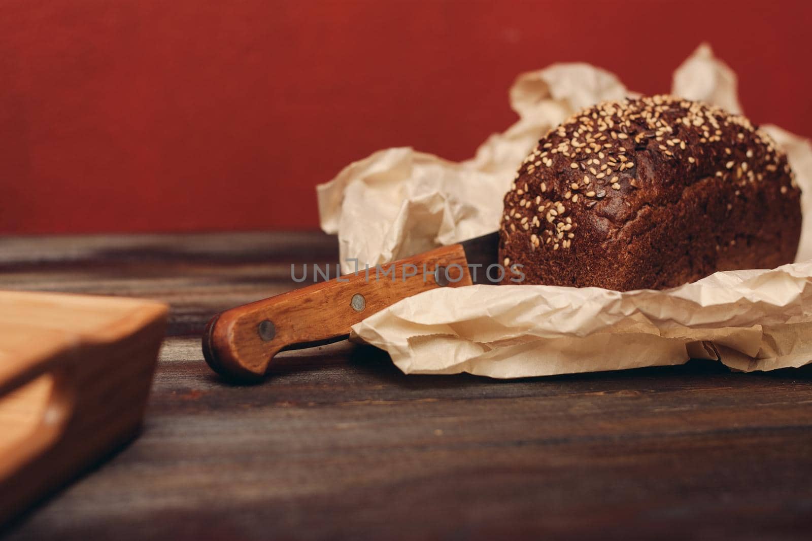 rye bread on a wooden table paper packaging sharp knife red background board. High quality photo
