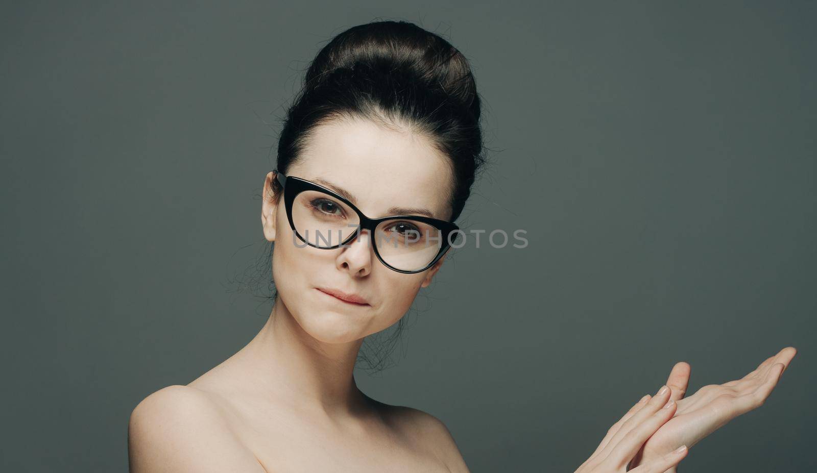 pretty brunette with glasses naked shoulders attractive look dark background. High quality photo