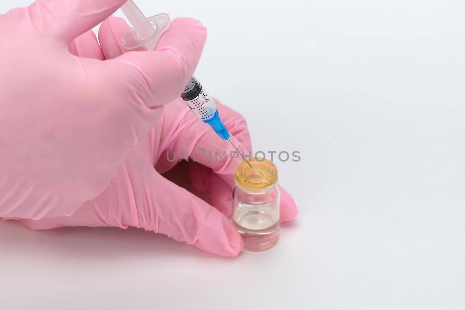 Vaccination of the population. A medical worker wearing medical gloves collects the vaccine into a disposable syringe. by Olga26