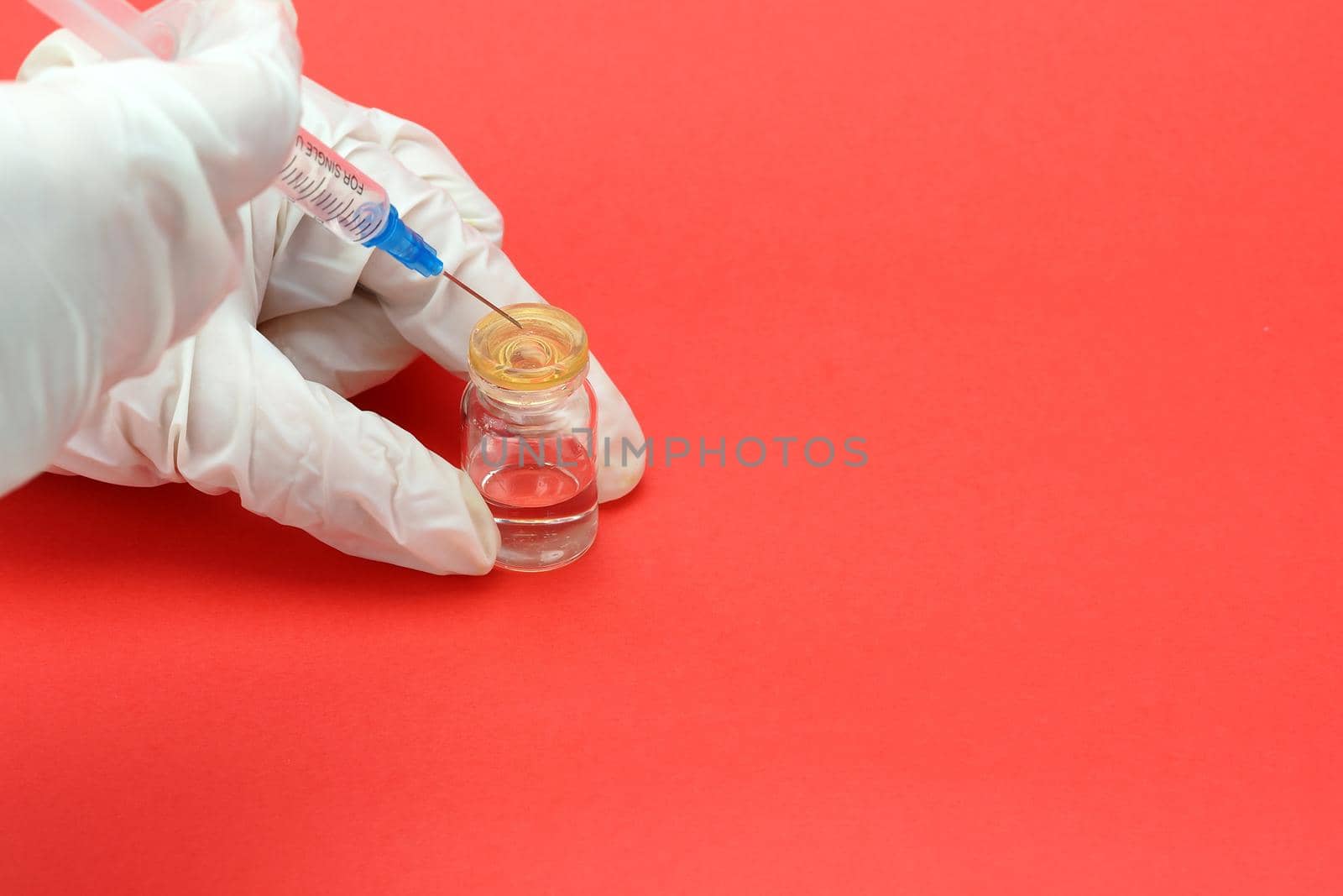 A doctor in medical gloves holds a syringe and a vial with a vaccine or drug in his hands. High quality photo