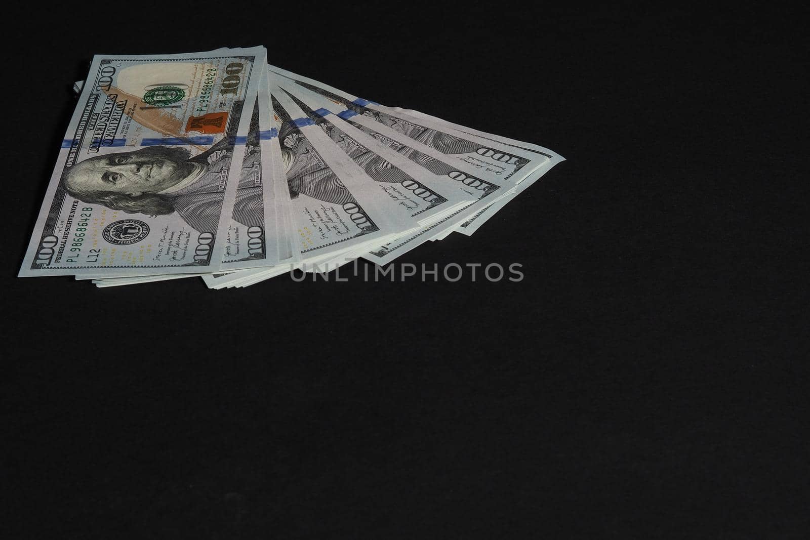 The American dollar. Paper bills of a hundred dollars on a black background. by Olga26