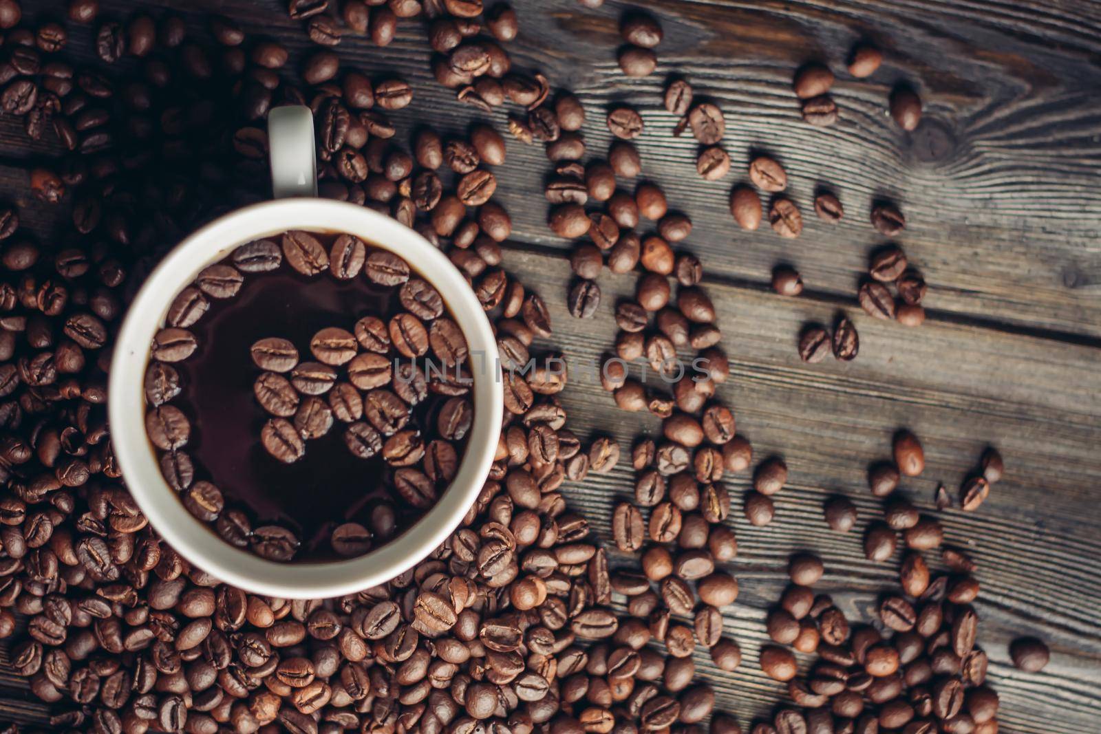 cup with aromatic drink and coffee beans on wooden background top view. High quality photo