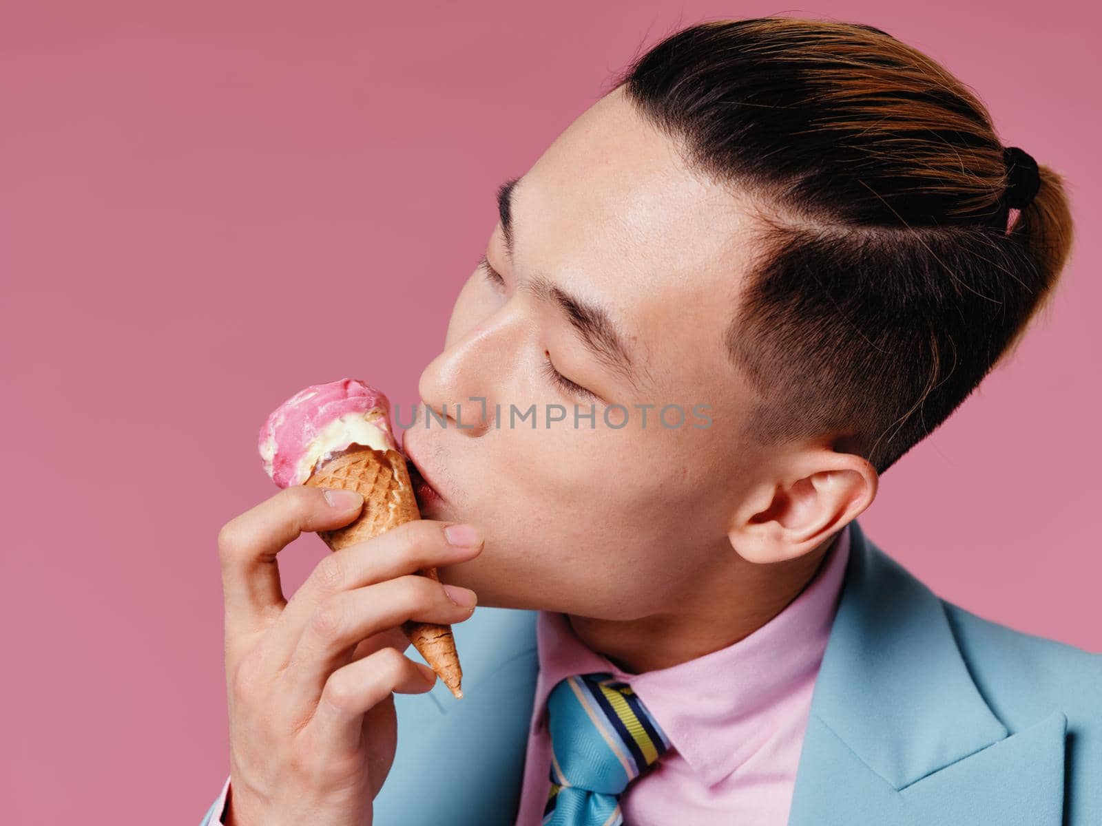 Handsome Asian male ice cream in a cone on a pink background brunet model. High quality photo