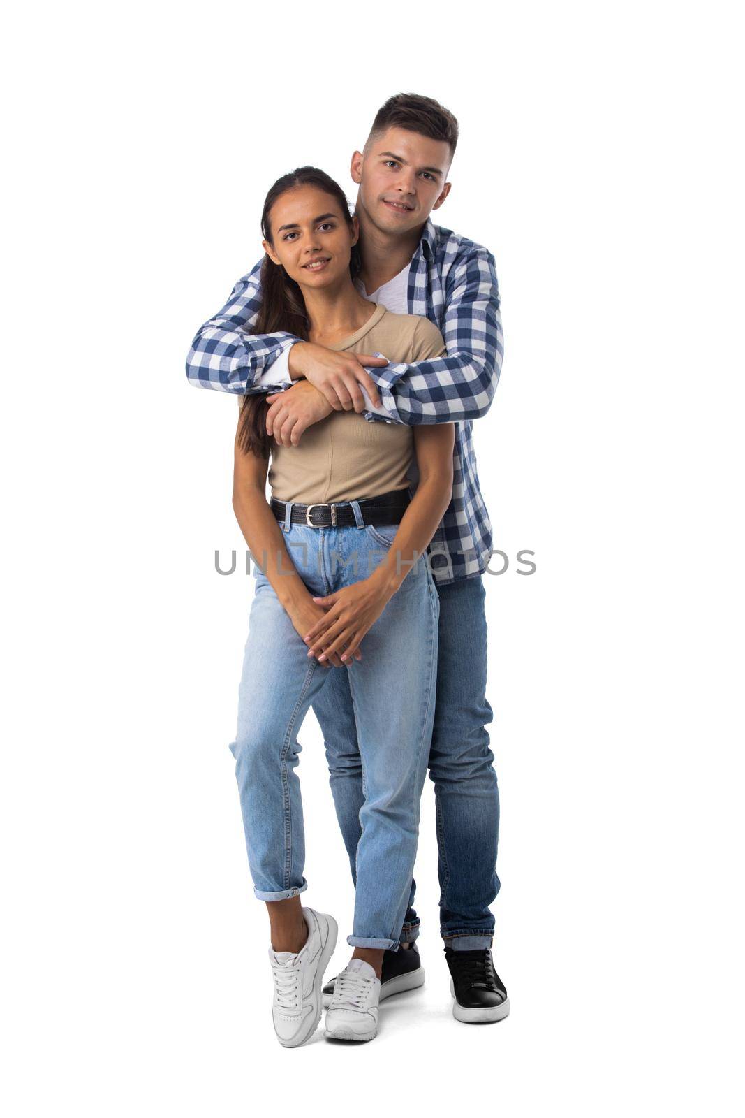 Smiling young couple embracing and standing full length isolated on white background