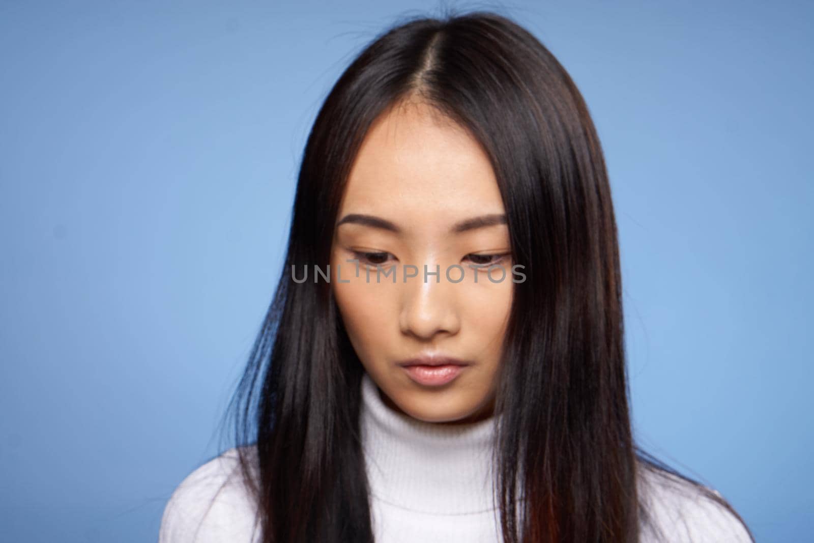 woman asian appearance portrait on blue background white sweater model. High quality photo