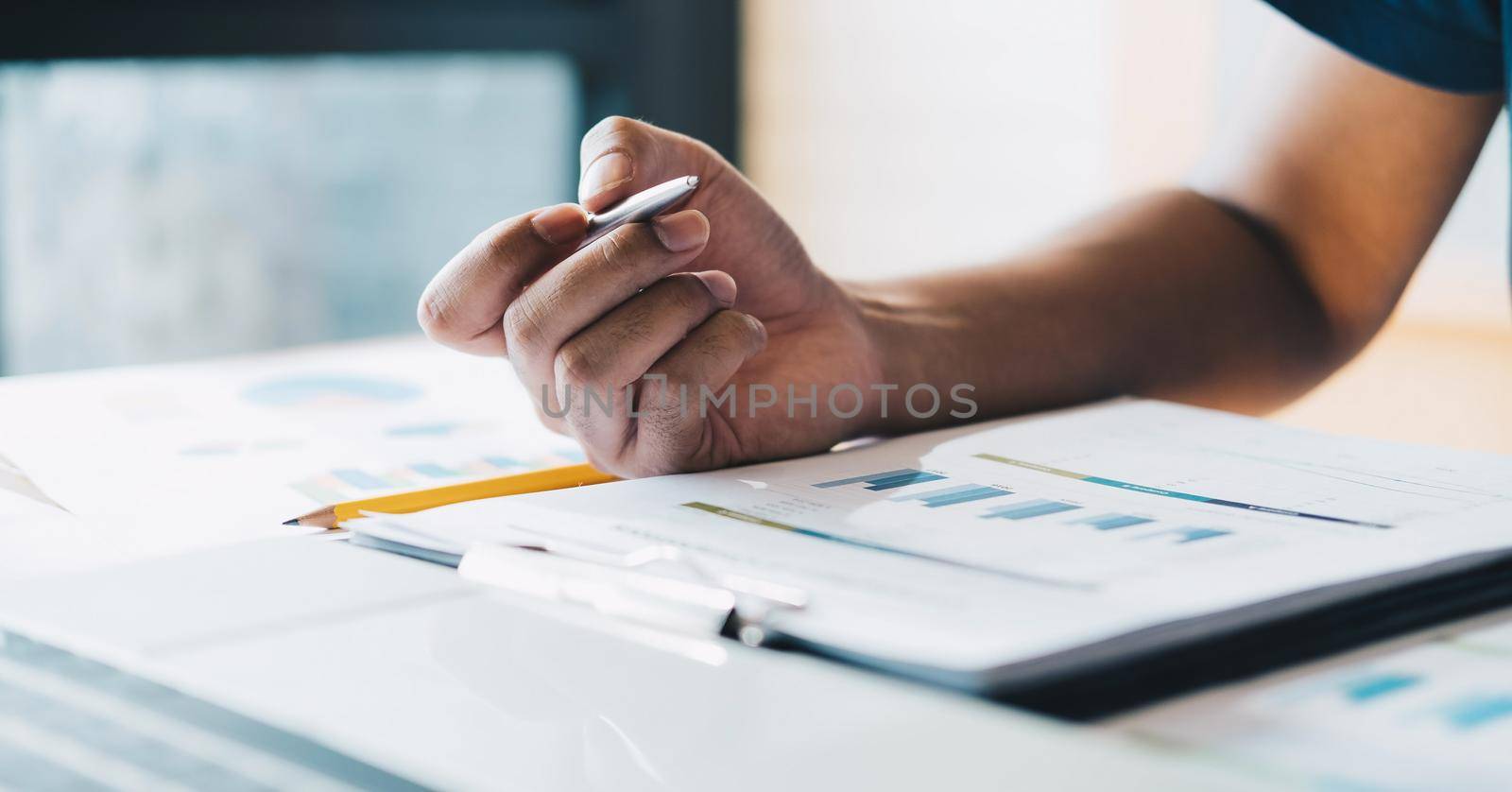 Close up accountant hand holding pen working on business finance data, accountancy document and laptop computer at office, business concept