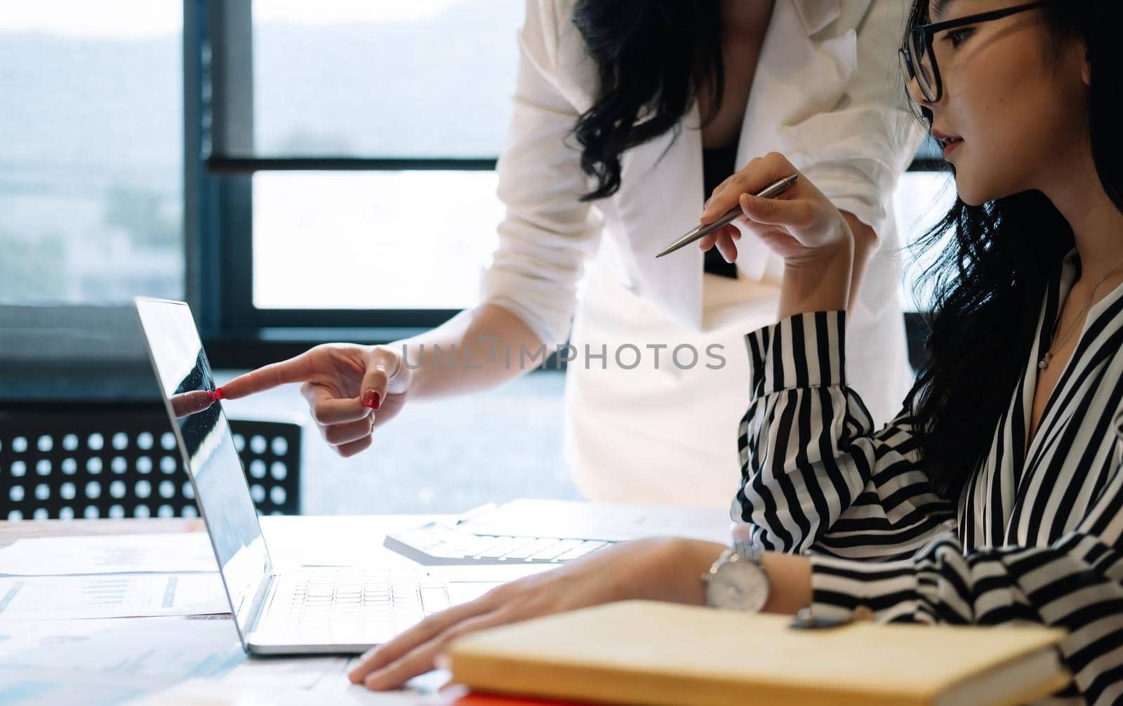 Business people meeting in office and discussing over a documents, two woman with a financial report with partner colleague on laptop computer by nateemee