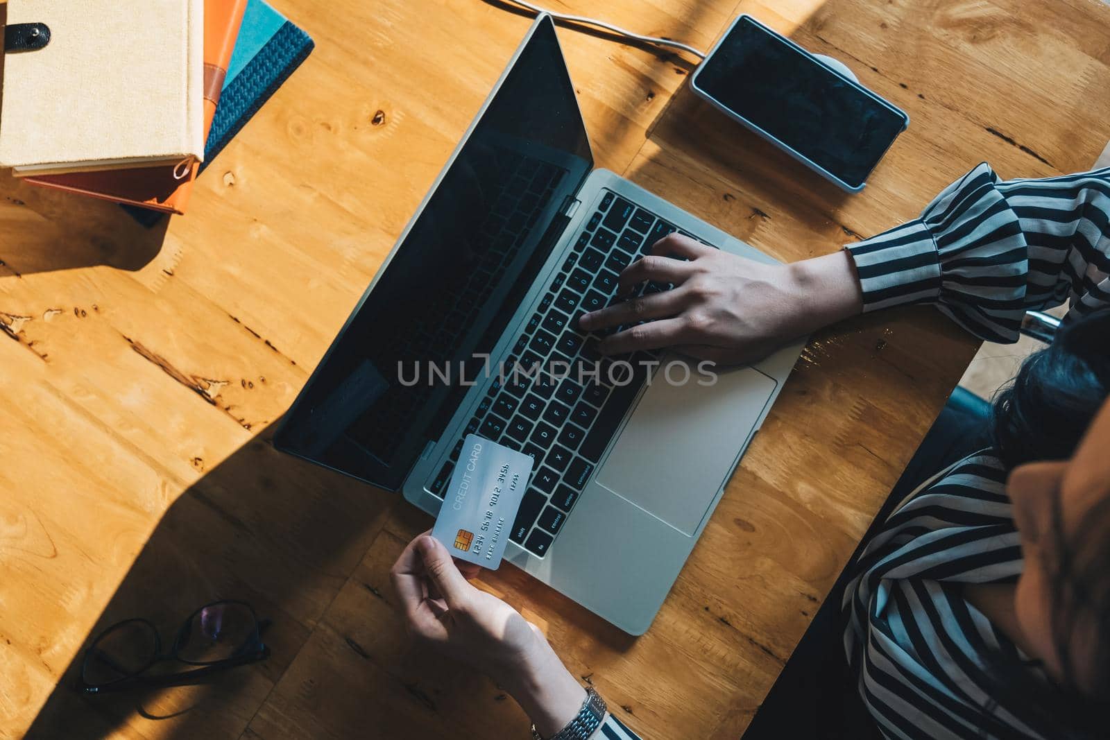 Online payment,Woman's hands holding a credit card and using laptop computer for online shopping, top view shot. by nateemee