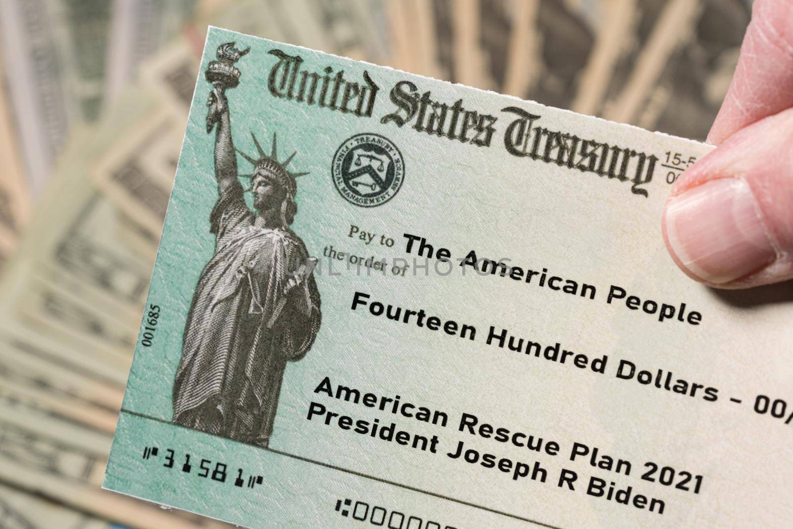 Stack of 20 dollar bills with US Treasury illustrative check to illustrate American Rescue Plan Act of 2021 payment on cash background