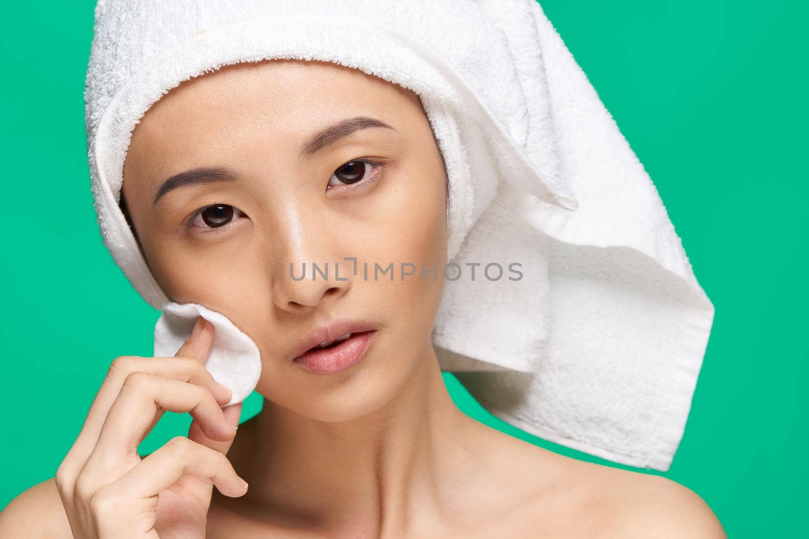 pretty asian woman bare shoulders towel on head cotton pad clean skin green background. High quality photo