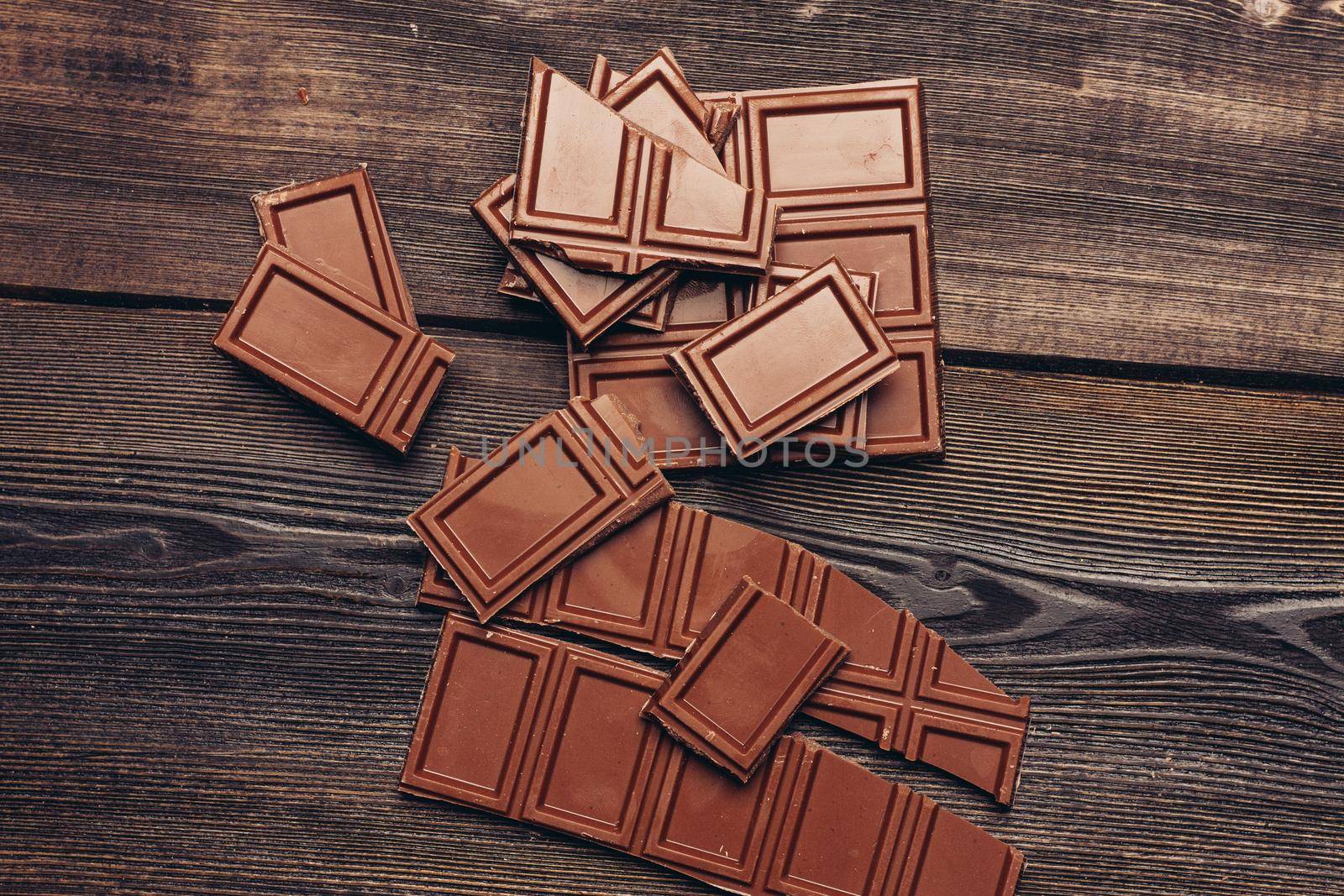 bar of chocolate broken into cubes on a wooden table. High quality photo