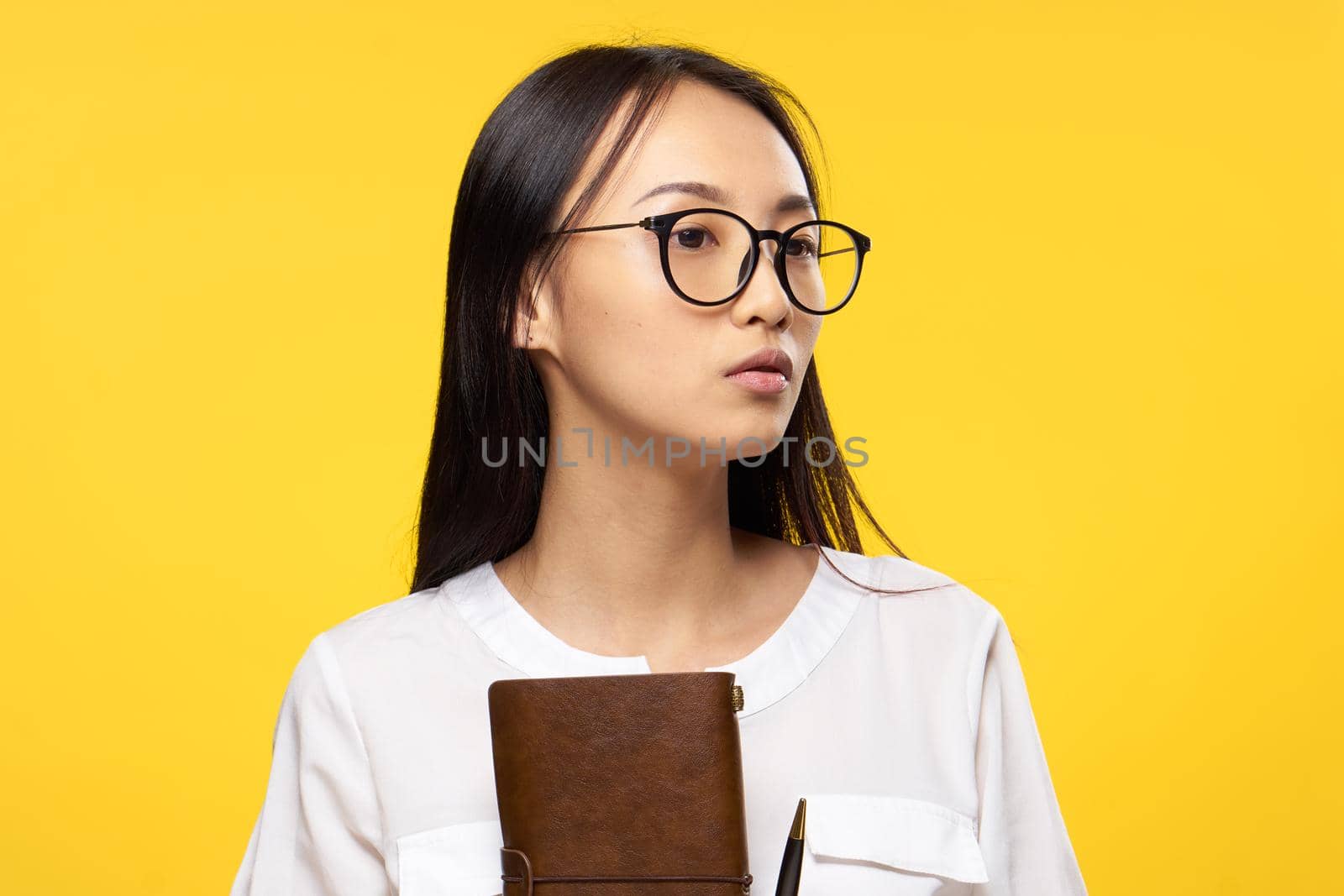 woman of asian appearance with notepad in hand glasses elegant style manager yellow background. High quality photo