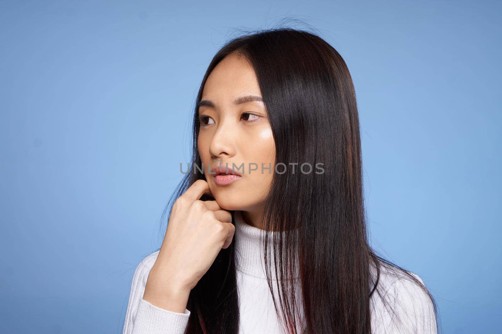 brunette asian touching face with hand makeup model white sweater. High quality photo