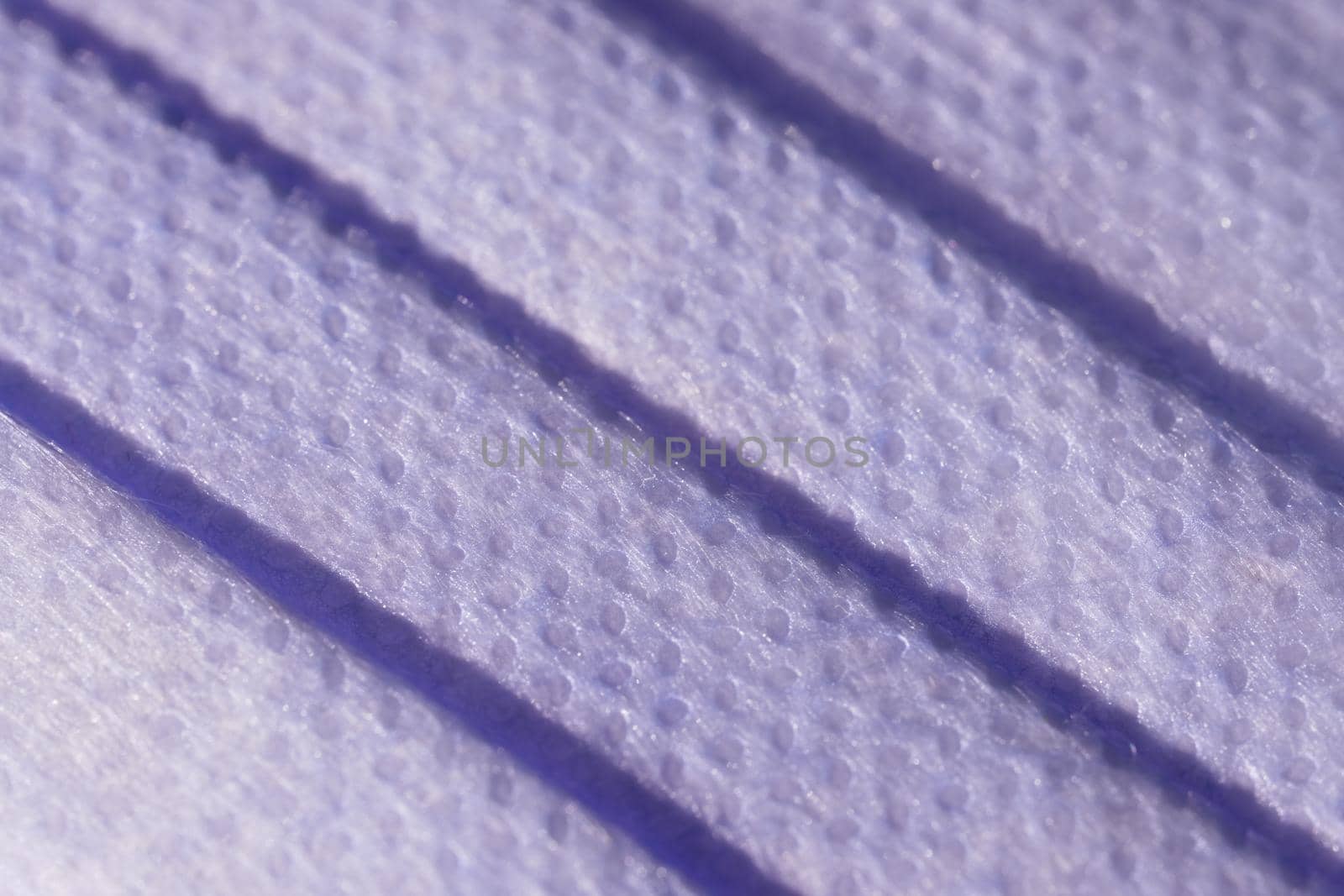 Super macro image showing the surface texture of a 3 ply single use face mask. Medical mask with 3 folds, splash proof and filtering ability.