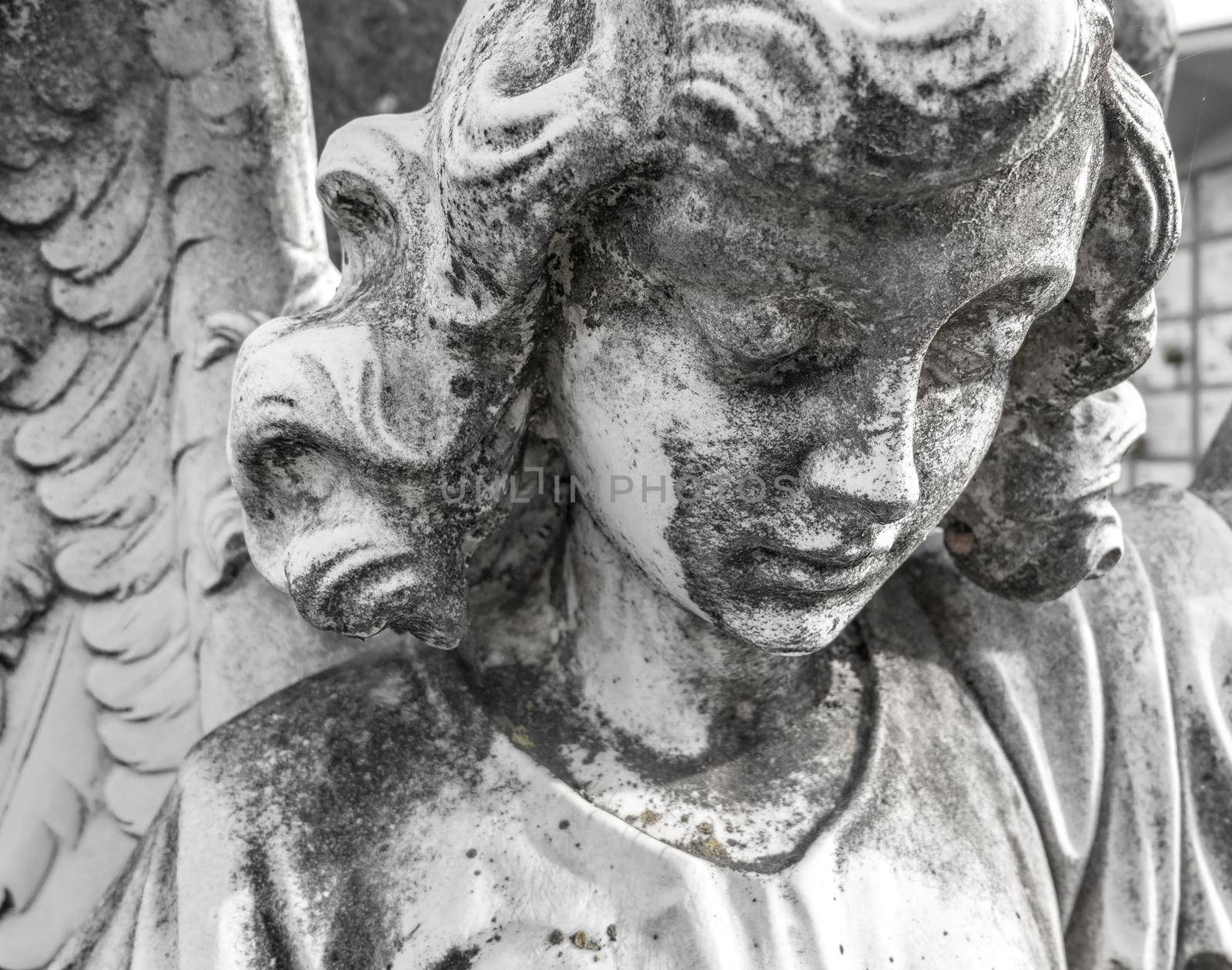 Black and white image of antique stone statue of sad angel. Religion, faith, death, resurrection, eternity concept.