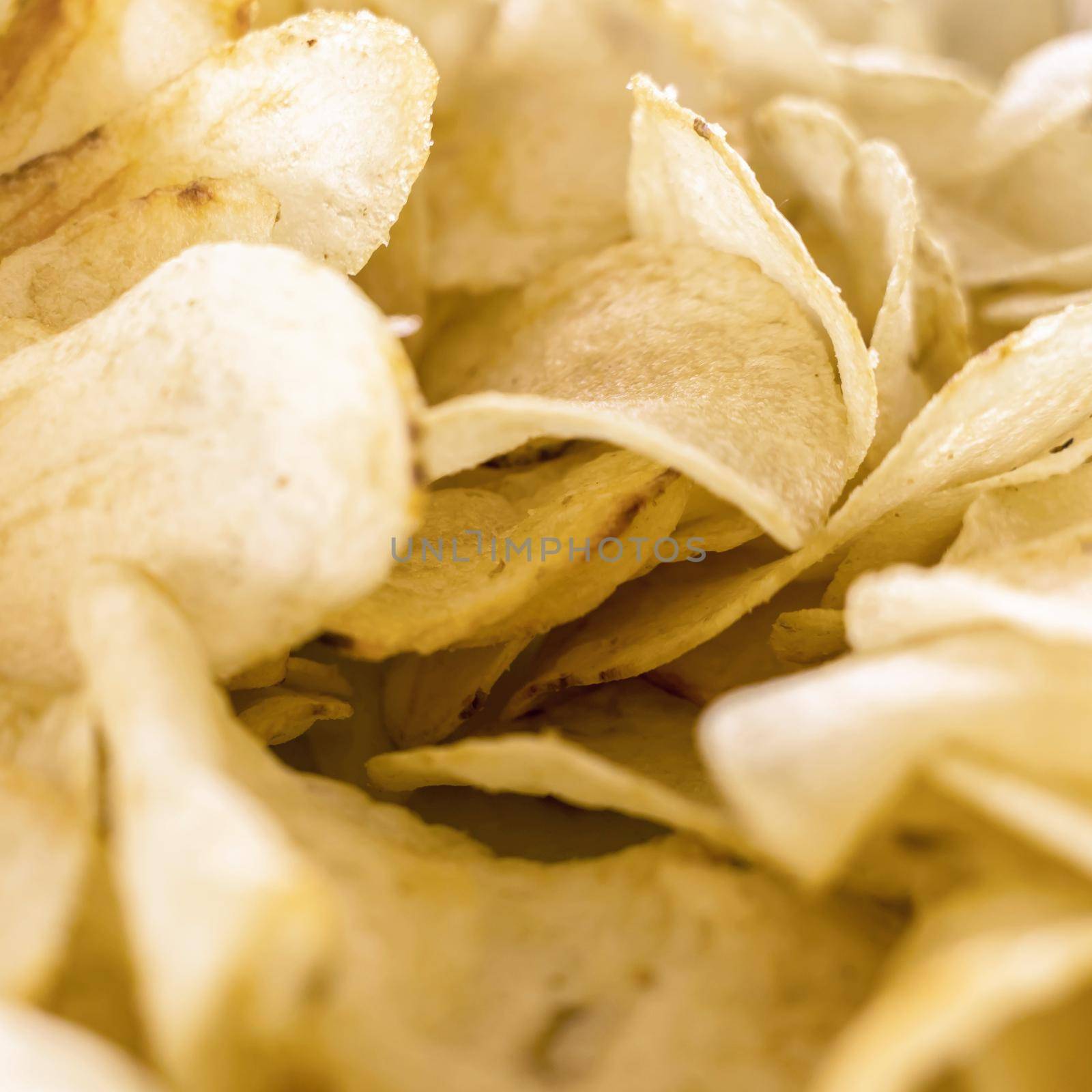 Yellow salted potato chips as background. Crispy chips golden pattern.