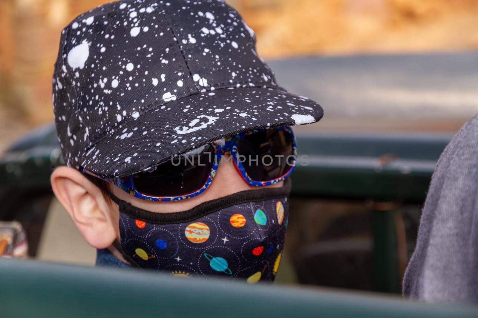 Portrait of a cute boy wearing a cap, face mask and sunglasses