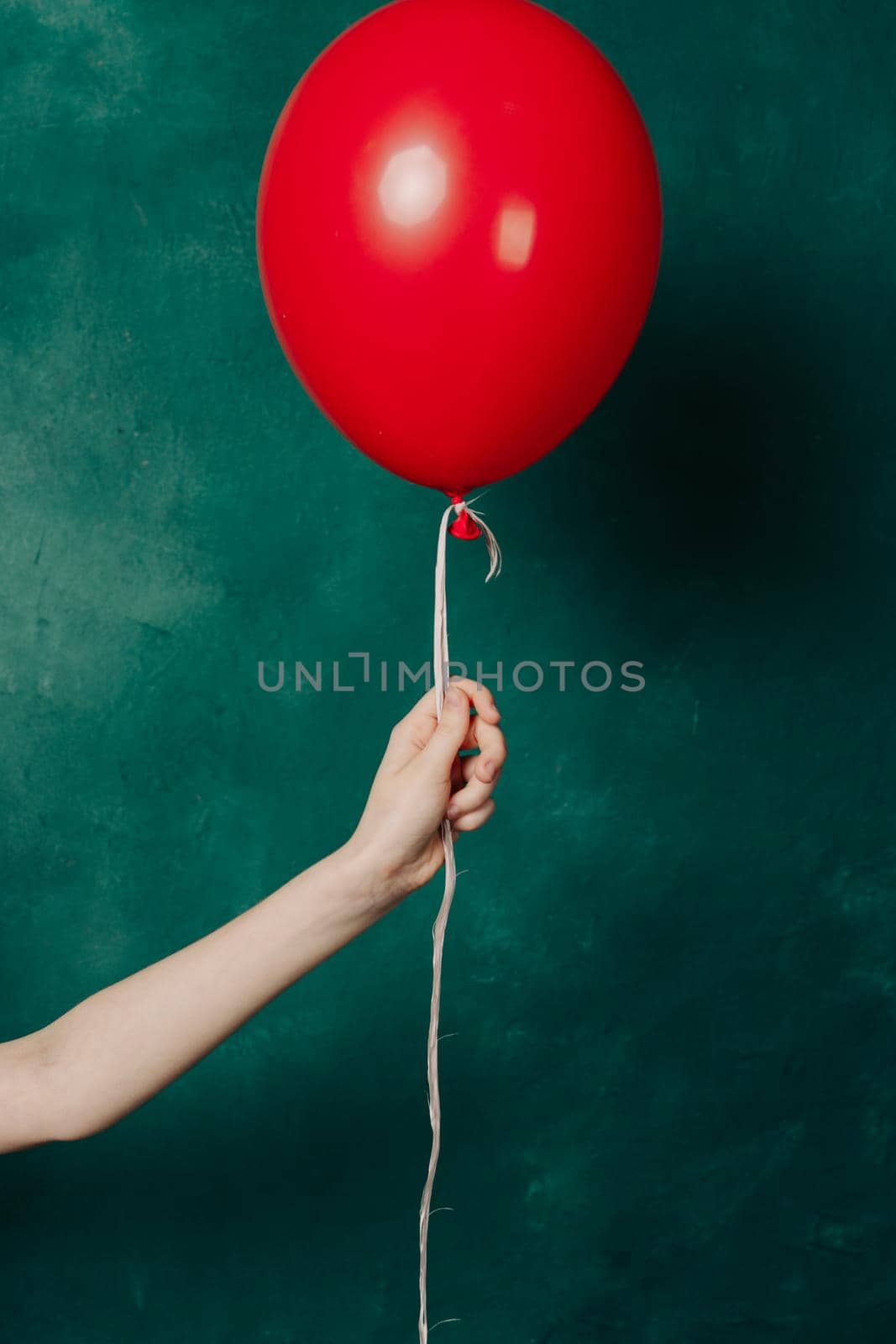 inflatable red balloon in a female hand on a green background close-up by SHOTPRIME