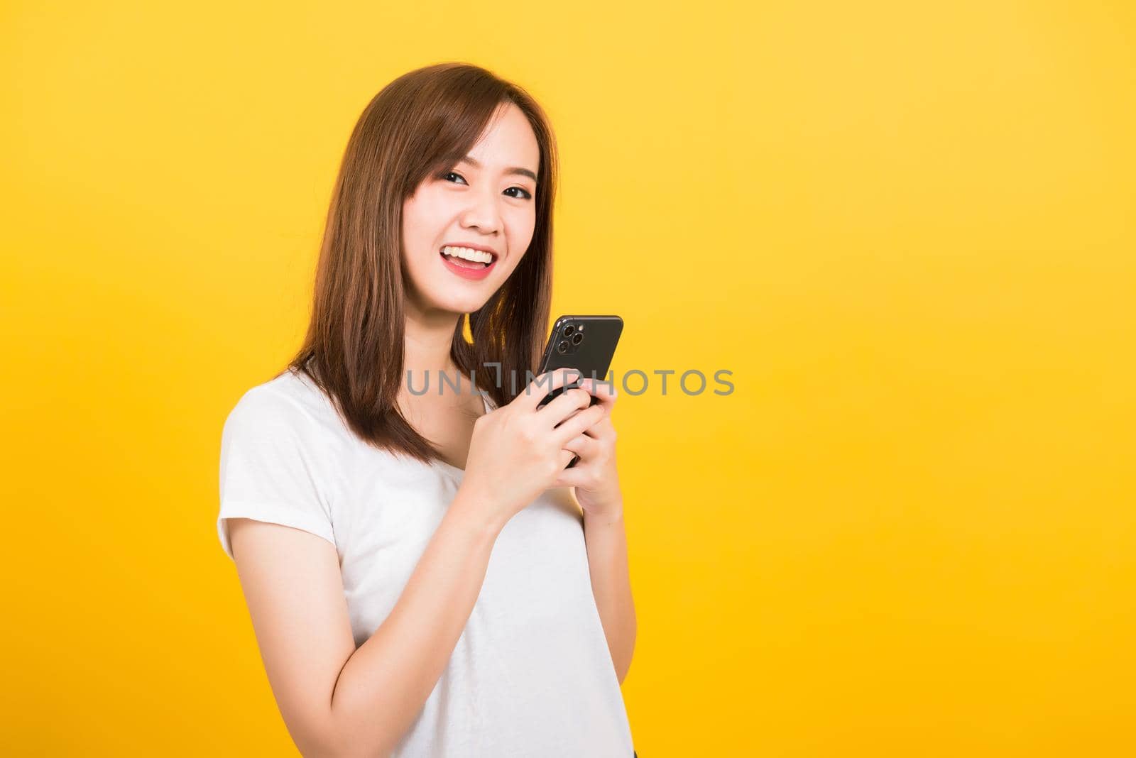 woman teen smiling standing wear t-shirt using smart mobile phone by Sorapop