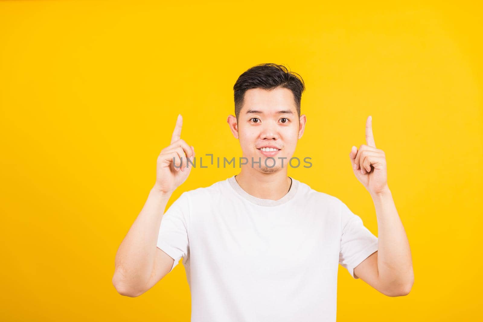 young man smiling standing pointing finger to above UP side by Sorapop