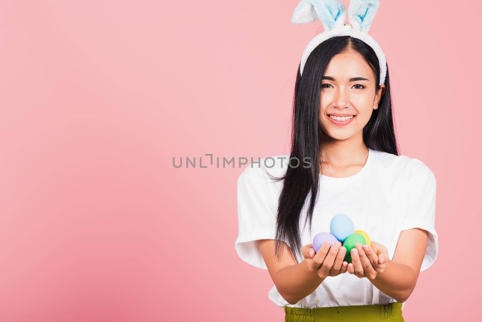 woman smiling wearing rabbit ears holding colorful Easter eggs gift on hands by Sorapop