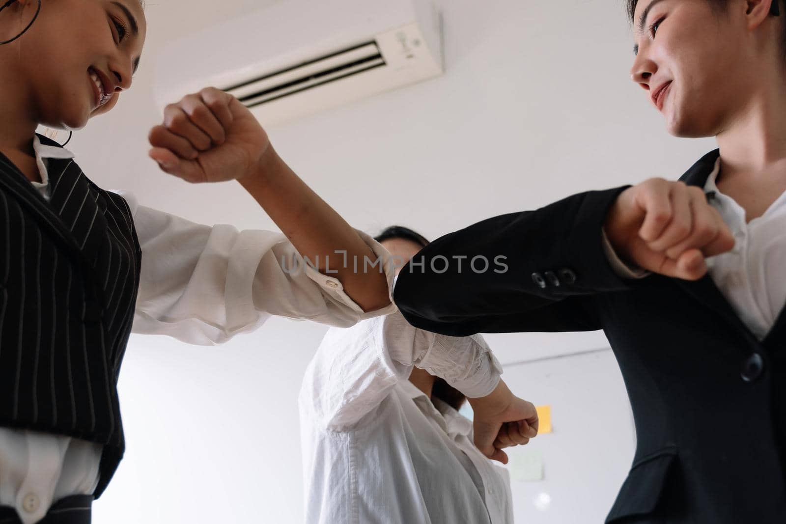 Group of business greeting bumping elbows at workplace, happy coworkers in medical facial covers protect from COVID-19 pandemics, healthcare concept. by nateemee