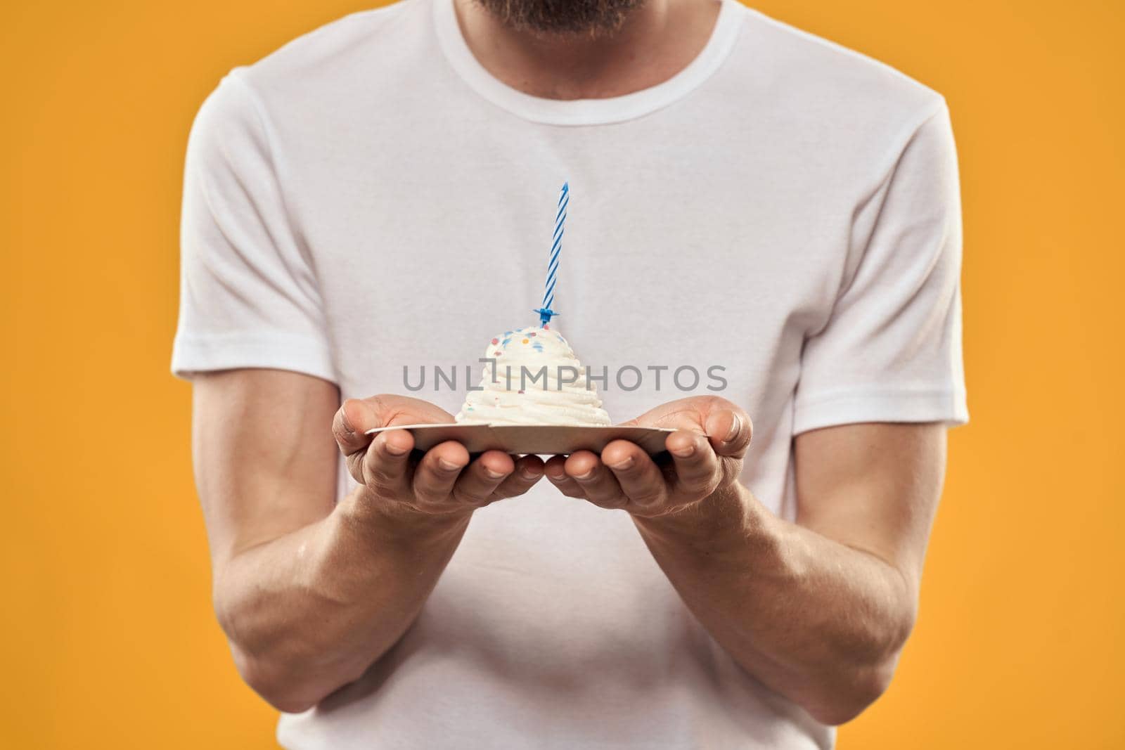 A man with a birthday cake in his hands on a yellow background birthday dessert. High quality photo