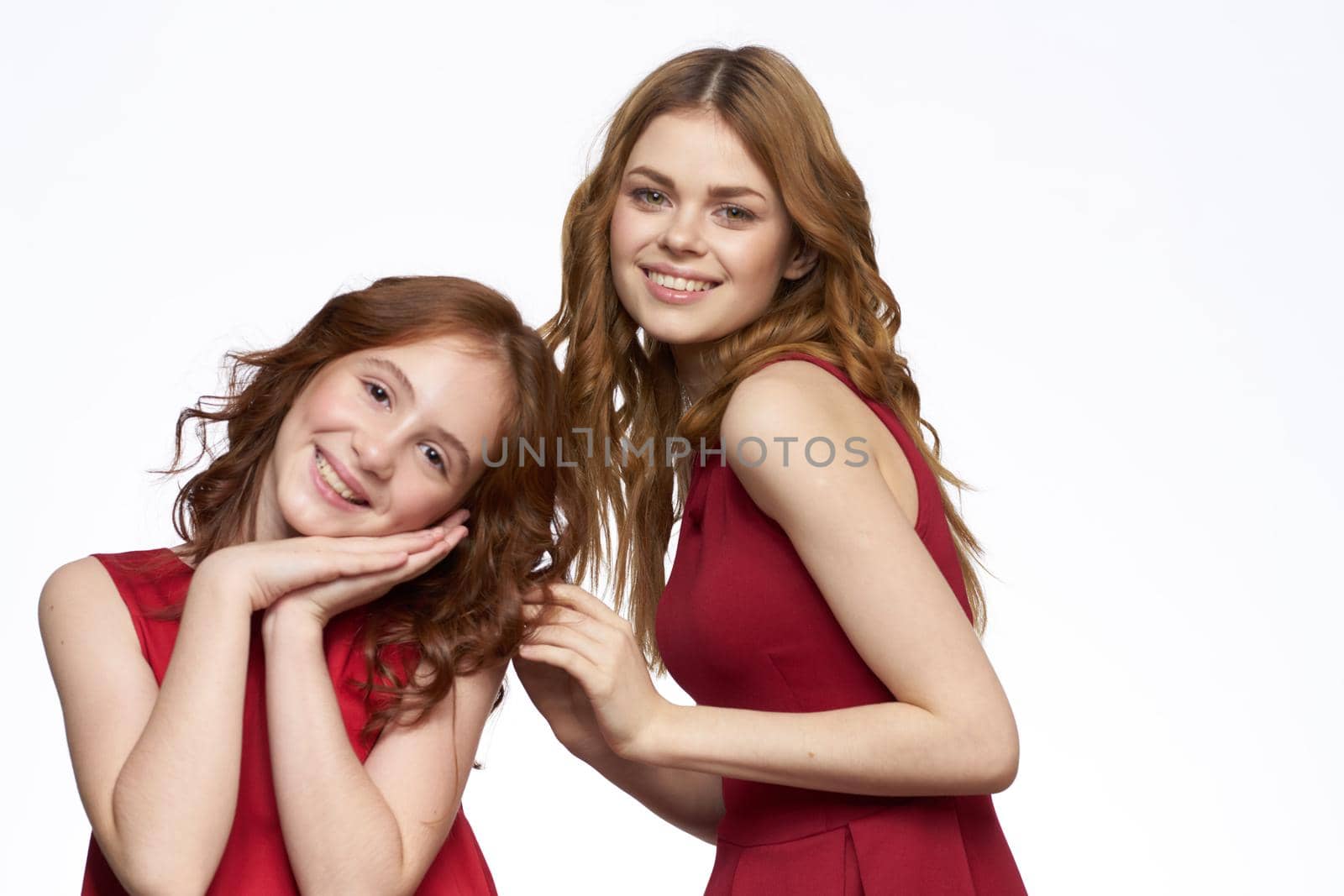 Cheerful mom and daughter next to red dresses hugs lifestyle light background smile. High quality photo