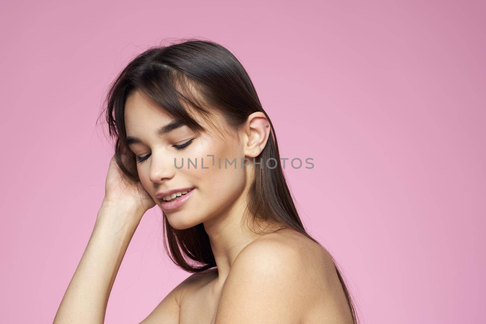 brunette bare shoulders clear skin body care pink background. High quality photo