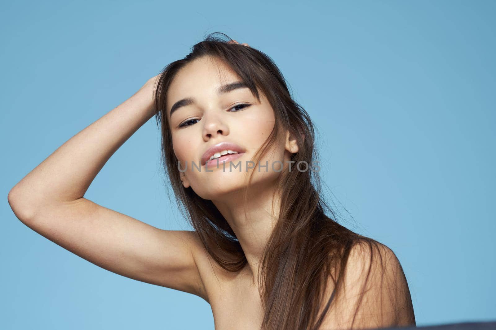 Woman with naked shoulders long hair cosmetics attractive look blue background. High quality photo