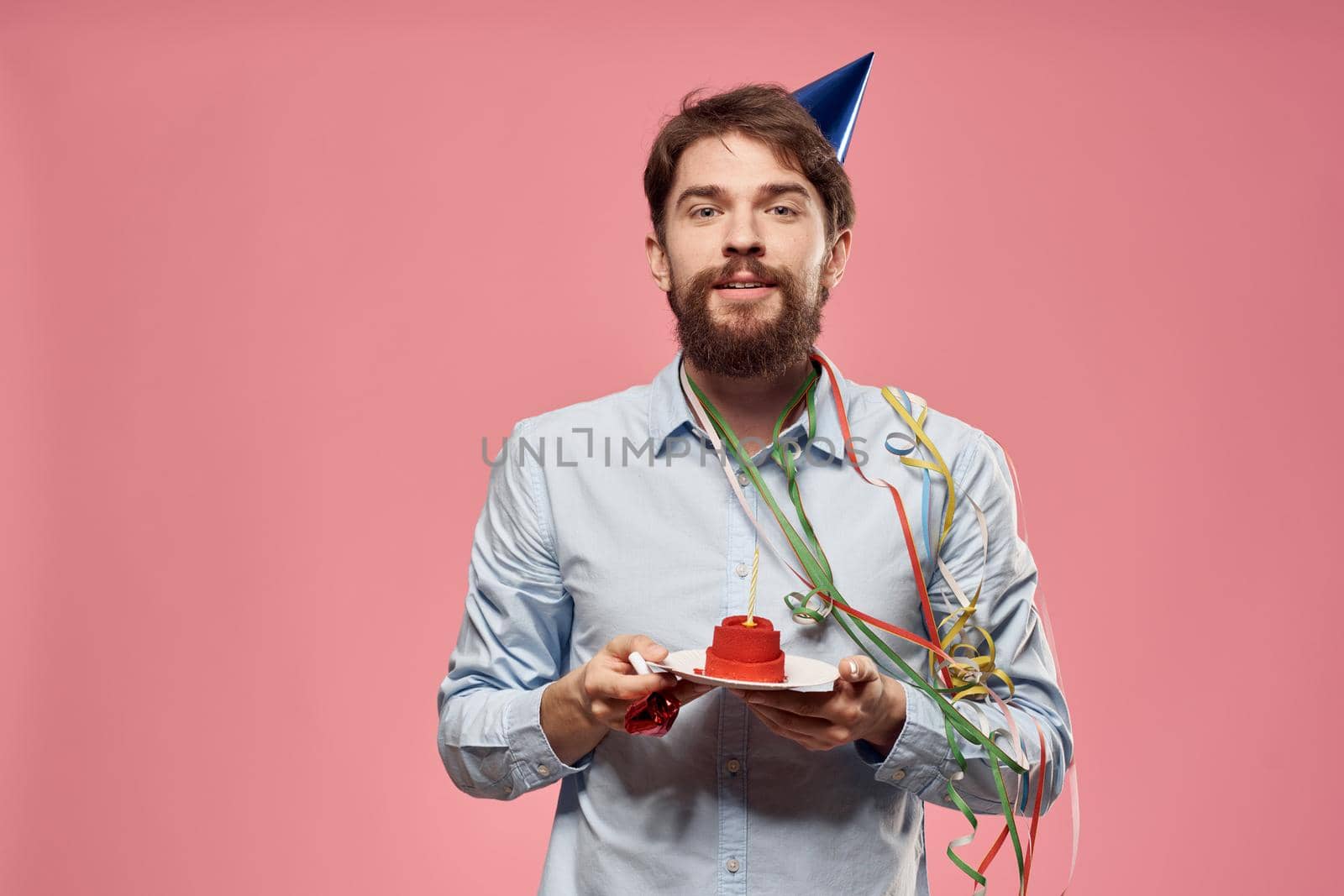 Bearded man with cake on pink background birthday party corporate emotions model loneliness. High quality photo