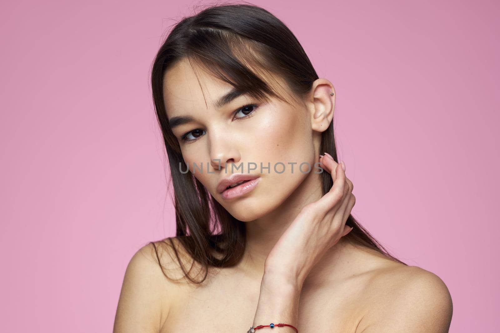 brunette bare shoulders clear skin body care pink background. High quality photo