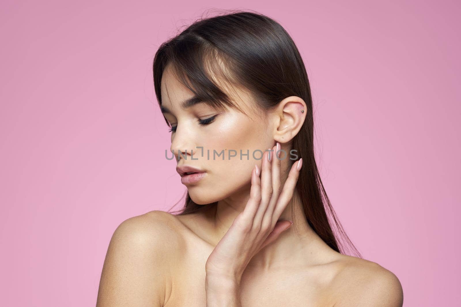 brunette bare shoulders clear skin body care pink background. High quality photo