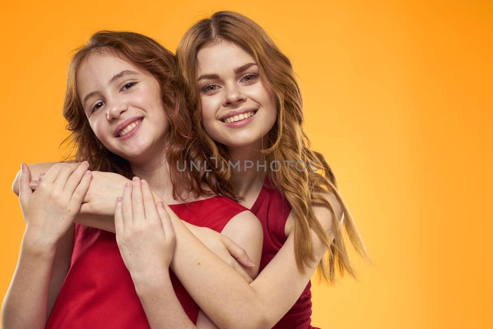 Mom and daughter in red dresses entertainment lifestyle yellow background. High quality photo