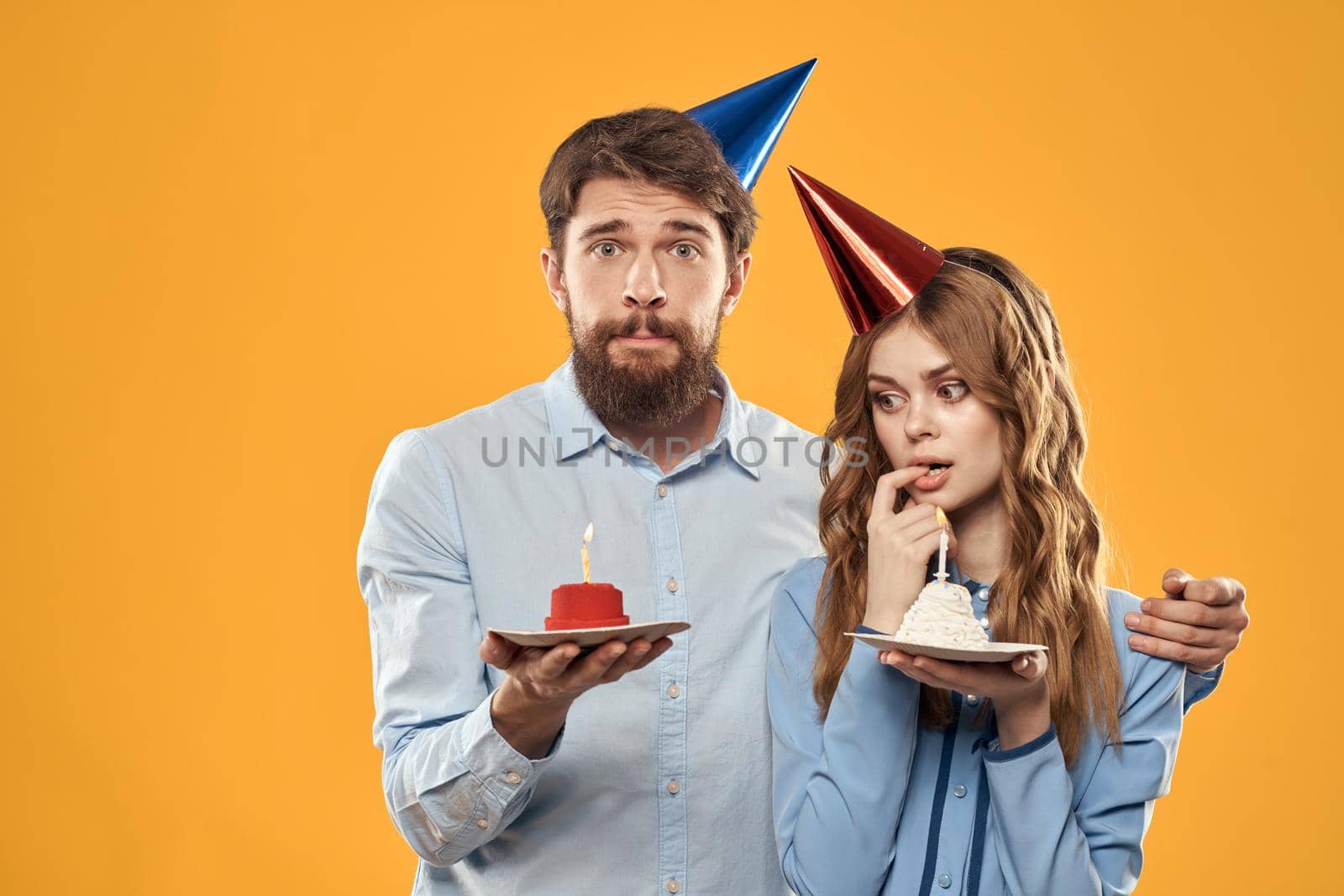 Man and woman at a party in caps and with tinsel cake fun yellow background. High quality photo